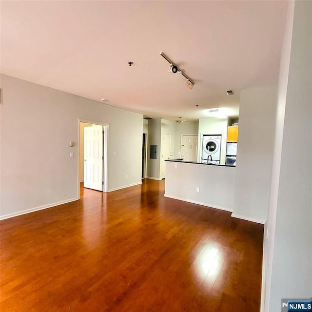 26 Ave At Port Imperial Unit 210, West New York, NJ 07093 - unfurnished living room with stacked washer / drying machine, track lighting, dark wood finished floors, and baseboards