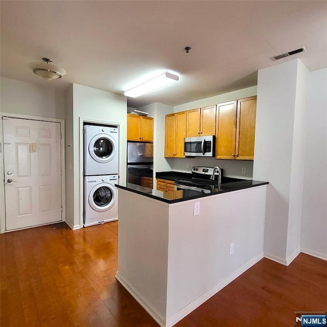 26 Ave At Port Imperial Unit 210, West New York, NJ 07093 - kitchen with stainless steel appliances, stacked washer and clothes dryer, dark wood-style floors, and a peninsula