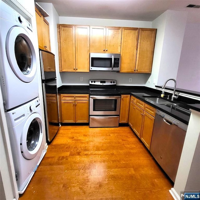 26 Ave At Port Imperial Unit 210, West New York, NJ 07093 - kitchen with stainless steel appliances, stacked washer / drying machine, a sink, light wood-type flooring, and dark countertops