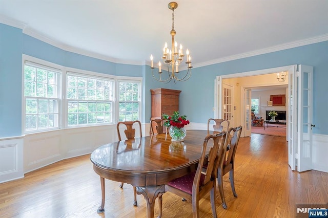 466 Park St, Montclair, NJ 07043 - dining space featuring a chandelier, light wood finished floors, a wainscoted wall, crown molding, and french doors