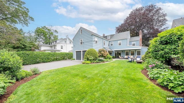 466 Park St, Montclair, NJ 07043 - rear view of house with a yard, an attached garage, driveway, and a chimney