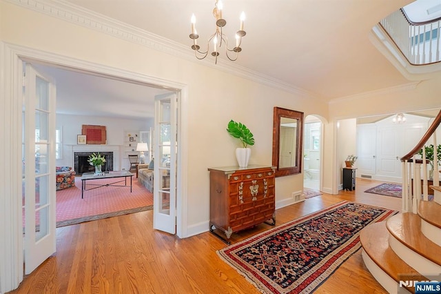 466 Park St, Montclair, NJ 07043 - foyer featuring light wood-style floors, ornamental molding, arched walkways, a chandelier, and a fireplace