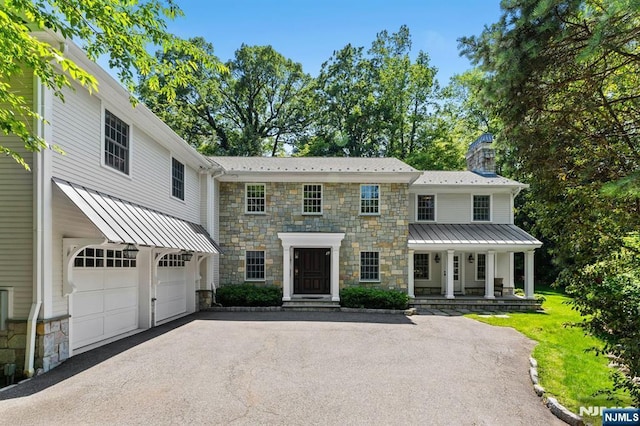 56 Knoll Rd, Tenafly, NJ 07670 - view of front of house featuring stone siding, driveway, a chimney, and a garage