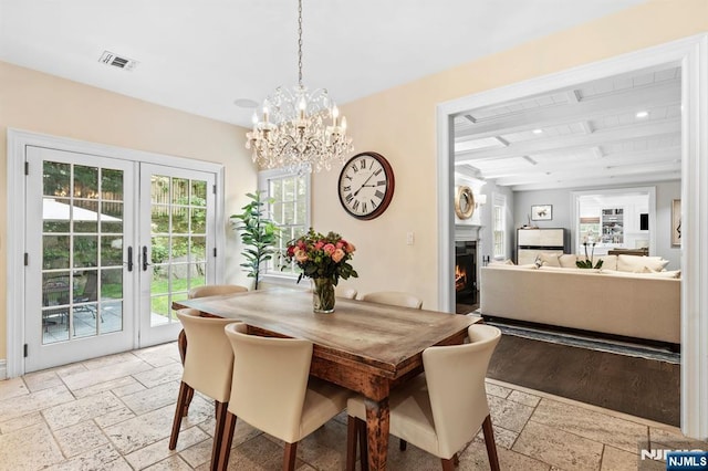 56 Knoll Rd, Tenafly, NJ 07670 - dining area with stone tile floors, beamed ceiling, french doors, a warm lit fireplace, and a chandelier