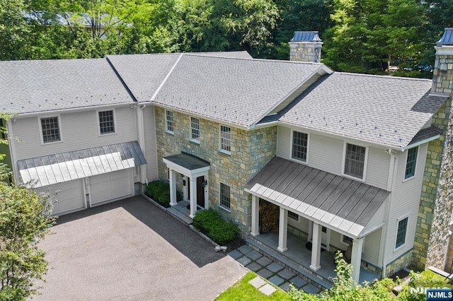 56 Knoll Rd, Tenafly, NJ 07670 - view of front of house featuring a chimney, a garage, stone siding, and asphalt driveway