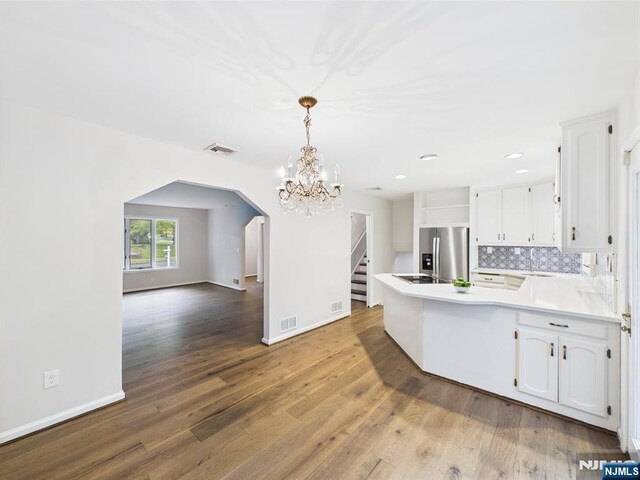 995 Andover Ter, Ridgewood, NJ 07450 - kitchen featuring arched walkways, stainless steel fridge with ice dispenser, a peninsula, a chandelier, and white cabinetry