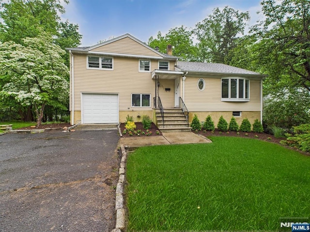 995 Andover Ter, Ridgewood, NJ 07450 - tri-level home featuring an attached garage, asphalt driveway, a front yard, and a chimney
