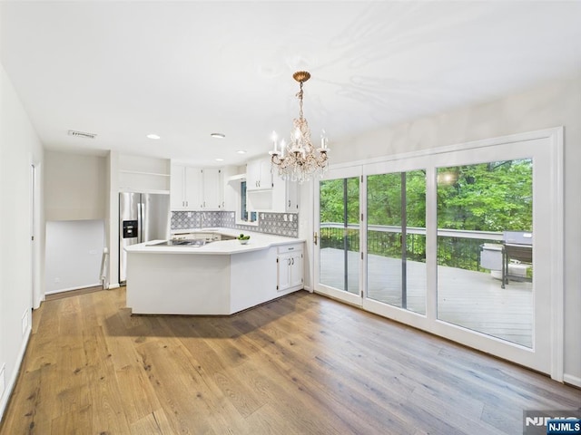 995 Andover Ter, Ridgewood, NJ 07450 - kitchen with stainless steel fridge, a peninsula, a chandelier, backsplash, and light countertops