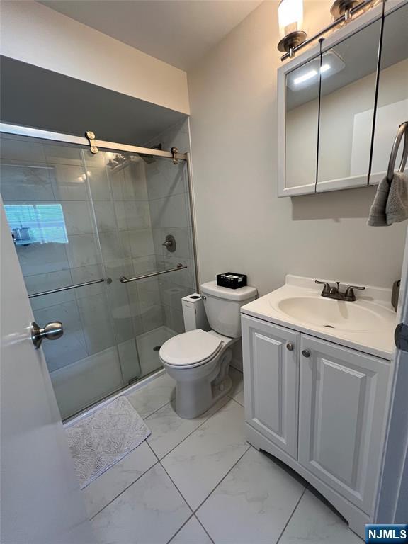 31 Fairmount Ave Unit 4A, Hackensack, NJ 07601 - full bathroom with marble look tiles, toilet, vanity, and a shower stall