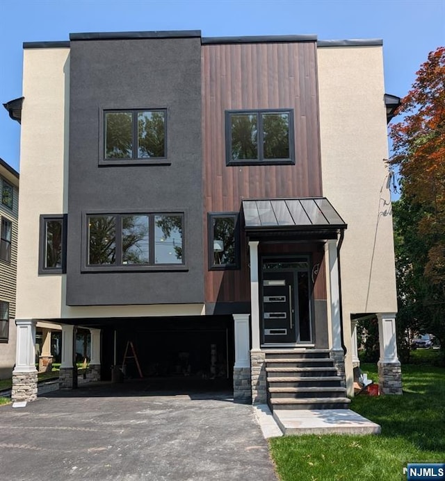 429 Riverside Ave, Rutherford, NJ 07070 - view of front facade with a standing seam roof, driveway, a garage, and stucco siding