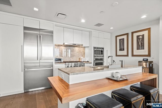 320 Adolphus Ave Unit 317, Cliffside Park, NJ 07010 - kitchen with built in appliances, white cabinets, dark wood-type flooring, under cabinet range hood, and a kitchen bar