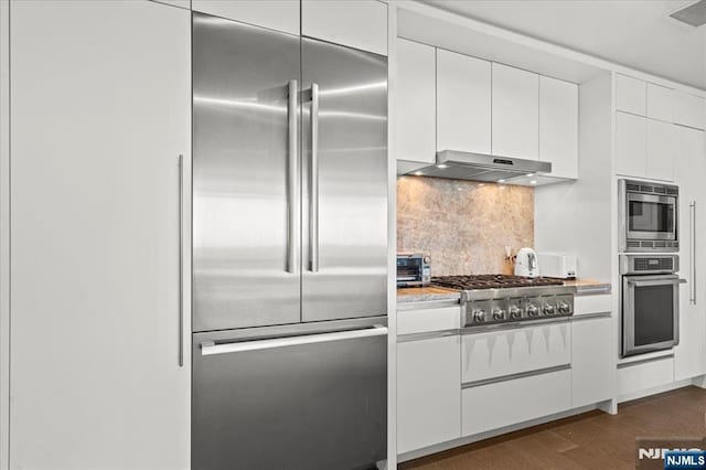 320 Adolphus Ave Unit 317, Cliffside Park, NJ 07010 - kitchen featuring stainless steel appliances, under cabinet range hood, white cabinetry, backsplash, and dark wood-style flooring