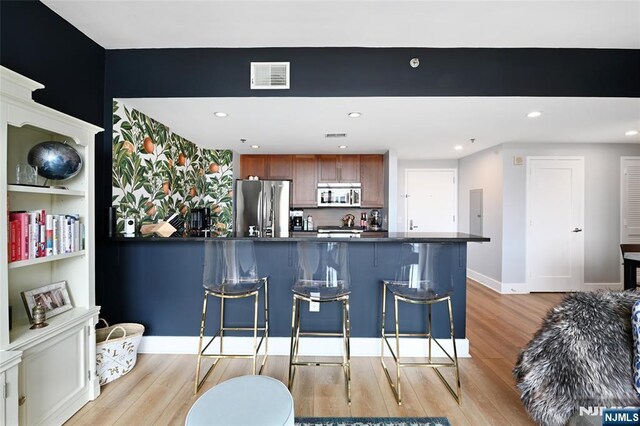 800 Jackson St Unit 505, Hoboken, NJ 07030 - kitchen with stainless steel appliances, light wood-style flooring, dark countertops, a breakfast bar area, and recessed lighting