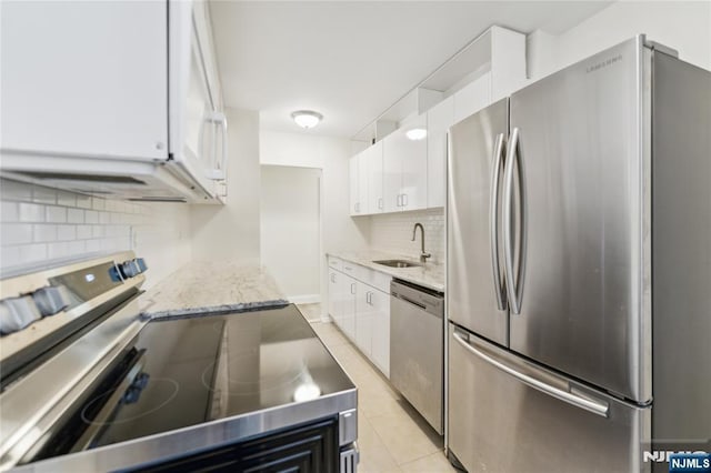 200 Winston Unit 121, Cliffside Park, NJ 07010 - kitchen featuring appliances with stainless steel finishes, a sink, backsplash, white cabinetry, and light stone countertops