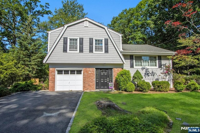 42 Lohs Pl, Harrington Park, NJ 07640 - view of front facade featuring a gambrel roof, a front lawn, an attached garage, driveway, and brick siding