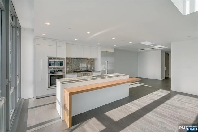 320 Adolphus Ave Unit 1115, Cliffside Park, NJ 07010 - kitchen with appliances with stainless steel finishes, modern cabinets, decorative backsplash, white cabinetry, and light wood-style flooring