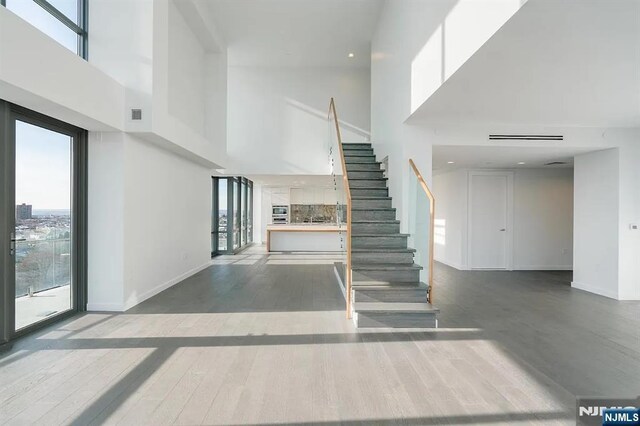 320 Adolphus Ave Unit 1115, Cliffside Park, NJ 07010 - unfurnished living room with a high ceiling, stairway, wood finished floors, and baseboards