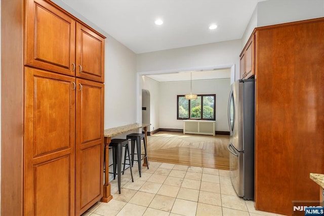 211 Harrison Ave, Hasbrouck Heights, NJ 07604 - kitchen featuring freestanding refrigerator, arched walkways, light stone countertops, brown cabinets, and recessed lighting