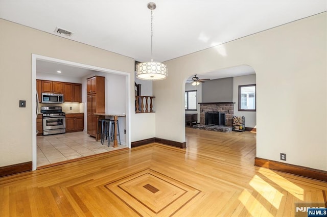 211 Harrison Ave, Hasbrouck Heights, NJ 07604 - unfurnished living room featuring ceiling fan, arched walkways, and a stone fireplace