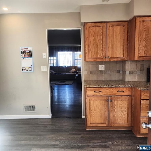 8 Tudor Pl Unit B08, Mount Olive Township, NJ 07828 - kitchen featuring baseboards, brown cabinetry, dark wood finished floors, dark stone countertops, and backsplash