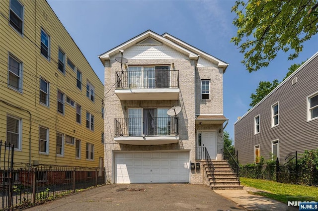 303-305 Runyon St, Newark, NJ 07108 - view of front facade with a balcony, asphalt driveway, a garage, and brick siding
