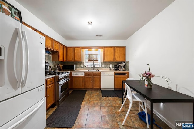 303-305 Runyon St, Newark, NJ 07108 - kitchen with stainless steel appliances, tasteful backsplash, brown cabinetry, light countertops, and a sink