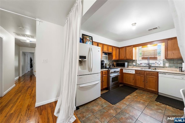 303-305 Runyon St, Newark, NJ 07108 - kitchen featuring appliances with stainless steel finishes, a sink, brown cabinetry, light countertops, and tasteful backsplash