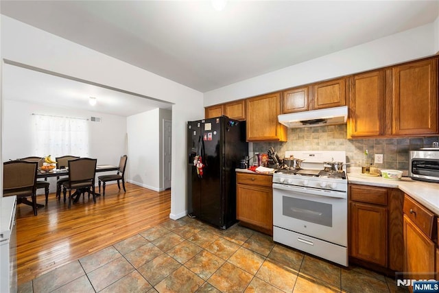 303-305 Runyon St, Newark, NJ 07108 - kitchen featuring white range with gas cooktop, under cabinet range hood, black refrigerator with ice dispenser, and brown cabinetry
