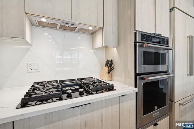 800 Ave At Port Imperial Blvd Unit 517, Weehawken, NJ 07086 - kitchen with under cabinet range hood, black gas cooktop, stainless steel double oven, and modern cabinets