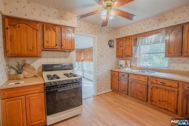 11 Newman Ave, Nutley, NJ 07110 - kitchen with gas range gas stove, wallpapered walls, a sink, light wood finished floors, and brown cabinets