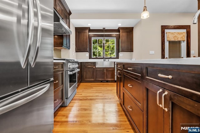 67 Woodland Rd, Bloomfield, NJ 07003 - kitchen featuring appliances with stainless steel finishes, light wood finished floors, under cabinet range hood, decorative light fixtures, and light countertops