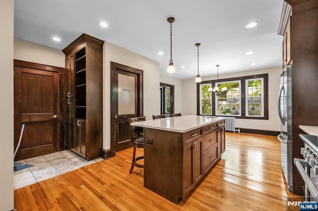 67 Woodland Rd, Bloomfield, NJ 07003 - kitchen featuring light wood finished floors, radiator heating unit, light countertops, a kitchen breakfast bar, and recessed lighting