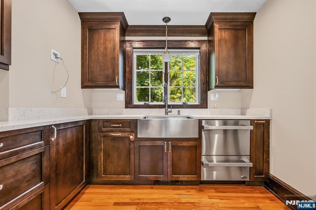 67 Woodland Rd, Bloomfield, NJ 07003 - kitchen with dishwasher, a sink, dark brown cabinets, light wood-type flooring, and decorative light fixtures