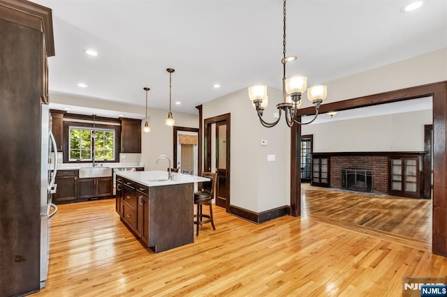 67 Woodland Rd, Bloomfield, NJ 07003 - kitchen featuring a sink, light countertops, a breakfast bar area, light wood finished floors, and dark brown cabinetry