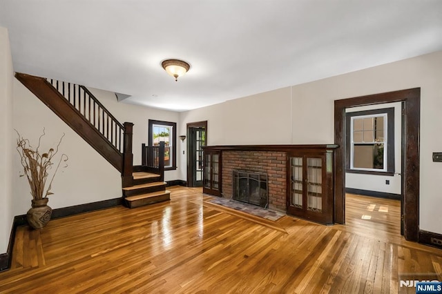 67 Woodland Rd, Bloomfield, NJ 07003 - unfurnished living room with wood finished floors, stairway, baseboards, and a brick fireplace