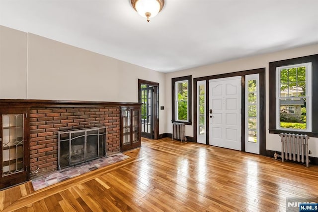 67 Woodland Rd, Bloomfield, NJ 07003 - entrance foyer featuring radiator, a brick fireplace, hardwood / wood-style flooring, and baseboards