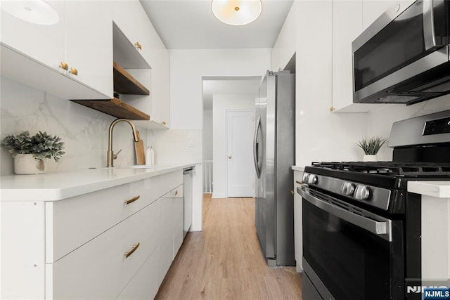 530 Broad Ave Unit 2, Englewood, NJ 07631 - kitchen with appliances with stainless steel finishes, a sink, white cabinetry, light wood finished floors, and light countertops