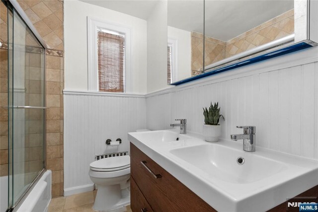 530 Broad Ave Unit 17, Englewood, NJ 07631 - full bath with toilet, double vanity, bath / shower combo with glass door, wainscoting, and tile patterned floors