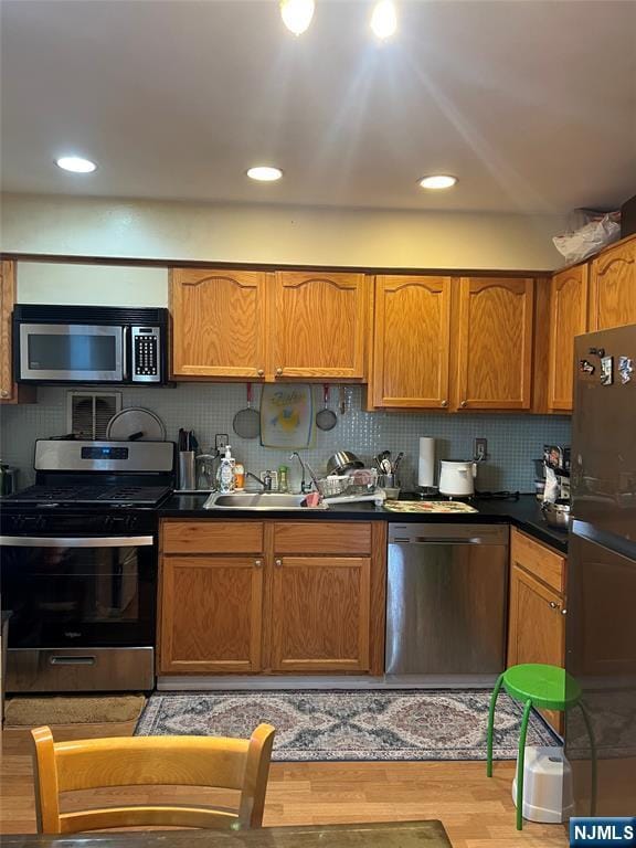 715 Broad Ave Unit 5A, Ridgefield, NJ 07657 - kitchen with appliances with stainless steel finishes, light wood-style flooring, backsplash, brown cabinets, and recessed lighting