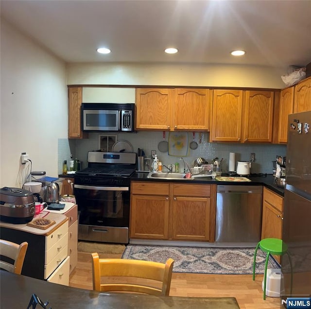 715 Broad Ave Unit 5A, Ridgefield, NJ 07657 - kitchen featuring appliances with stainless steel finishes, tasteful backsplash, light wood-style floors, brown cabinets, and recessed lighting