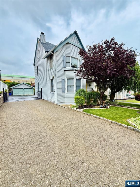 22 Church St, Nutley, NJ 07110 - view of front of property featuring a chimney, driveway, an outdoor structure, and a front yard