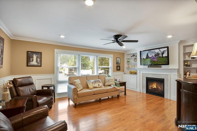 5 Edgewood Ct, Ringwood, NJ 07456 - living area featuring crown molding, a warm lit fireplace, ceiling fan, a wainscoted wall, and wood finished floors