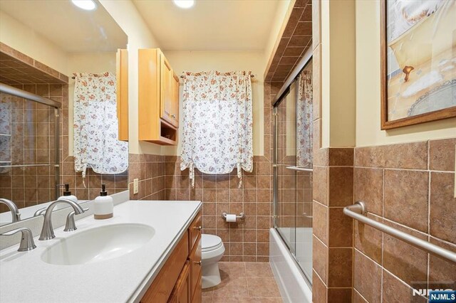 5 Edgewood Ct, Ringwood, NJ 07456 - full bath with tile walls, tile patterned floors, vanity, enclosed tub / shower combo, and a wainscoted wall