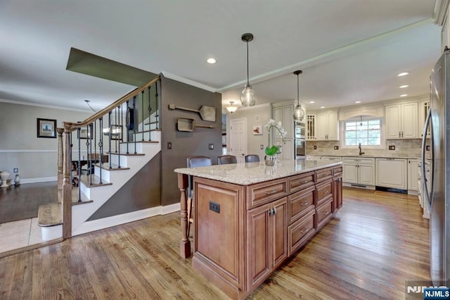 14 Swan Ct, East Rutherford, NJ 07073 - kitchen with light wood-style floors, appliances with stainless steel finishes, a kitchen island, light stone countertops, and a breakfast bar area