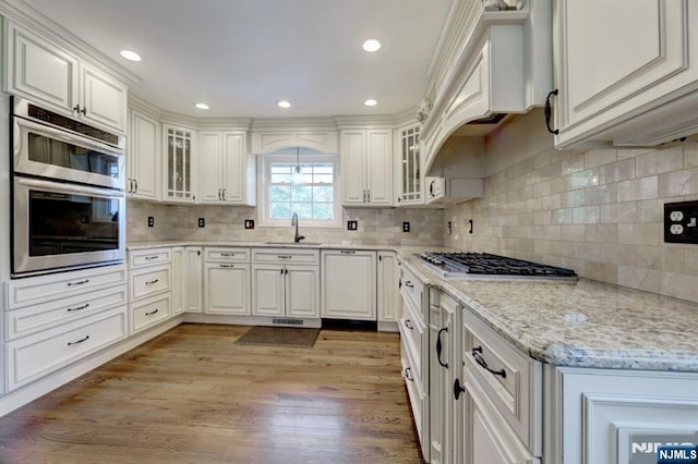 14 Swan Ct, East Rutherford, NJ 07073 - kitchen with appliances with stainless steel finishes, light wood finished floors, backsplash, light stone countertops, and recessed lighting