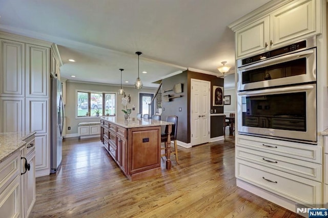14 Swan Ct, East Rutherford, NJ 07073 - kitchen with stainless steel appliances, light stone counters, light wood-style flooring, crown molding, and a breakfast bar