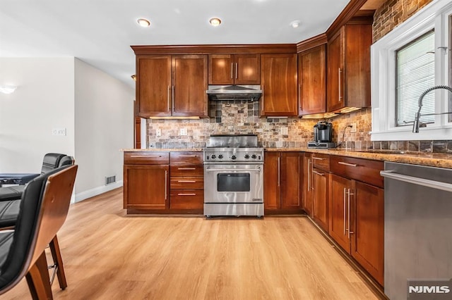 28 Elizabeth Ct, Secaucus, NJ 07094 - kitchen with appliances with stainless steel finishes, under cabinet range hood, light wood-style floors, stone counters, and backsplash
