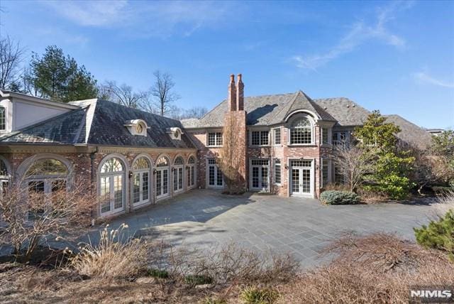 11 Margo Way, Alpine, NJ 07620 - back of property with french doors, a patio area, a chimney, and brick siding