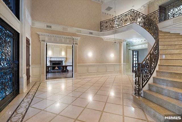 11 Margo Way, Alpine, NJ 07620 - tiled foyer featuring a towering ceiling, a decorative wall, inlaid floor details, stairs, and a fireplace