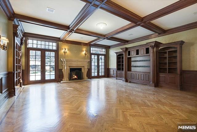 11 Margo Way, Alpine, NJ 07620 - unfurnished living room with french doors, a wainscoted wall, a decorative wall, beam ceiling, and coffered ceiling
